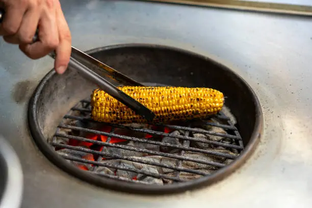 Asando una mazorca de maíz al carbón
